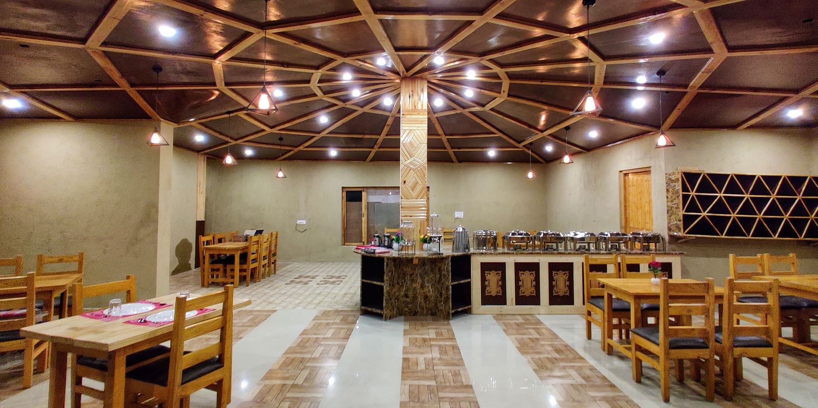The interior of a dining area with wooden tables and chairs at White Sands Resort, Ladakh.