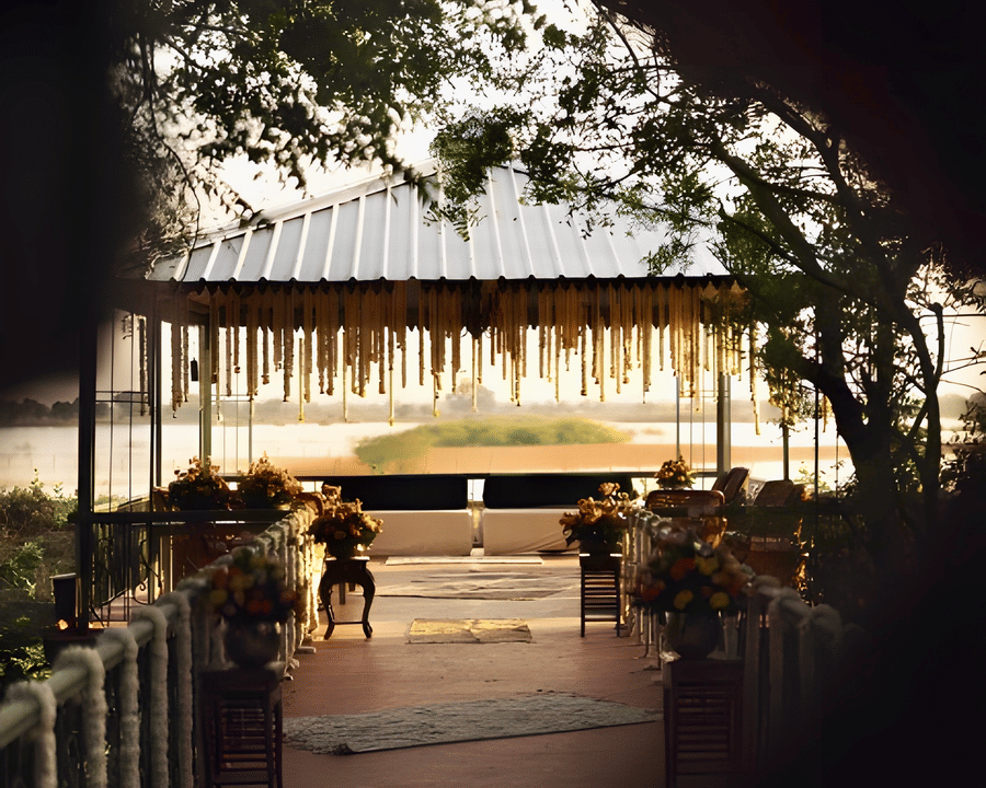 View of lit venue framed by trees at Umaid Palace during Charvi & Dhruv wedding event.