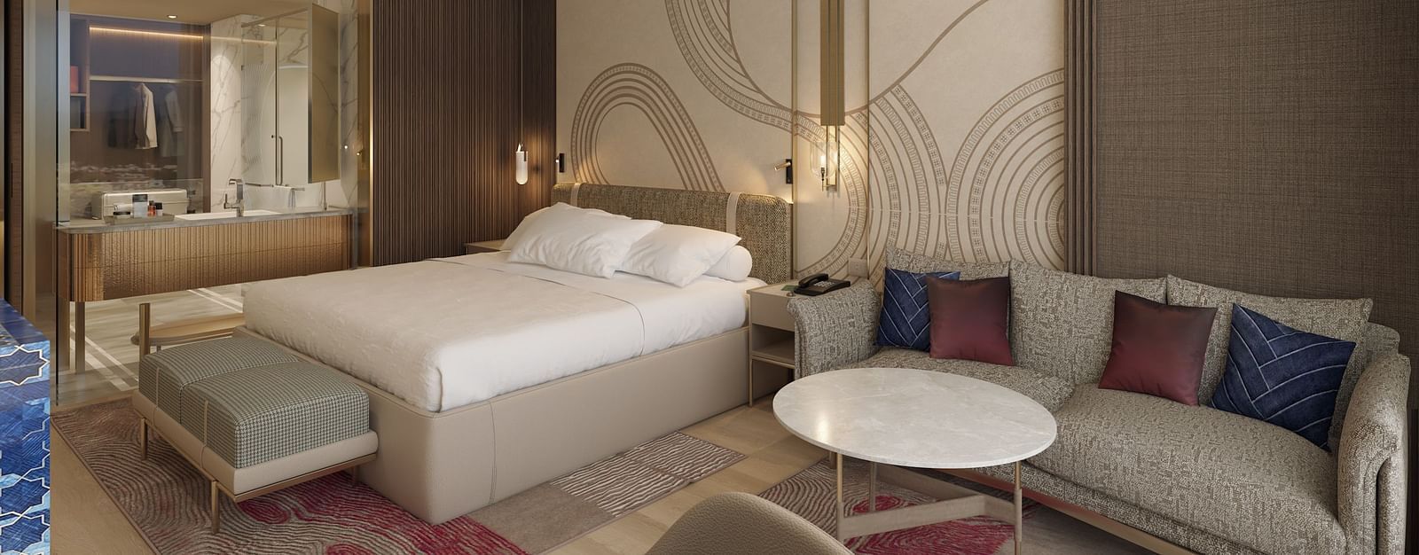 A side view of a modern hotel room with a large bed, seating area featuring a sofa and round table, and a vanity mirror in the background at Merlis Hotel, Coimbatore