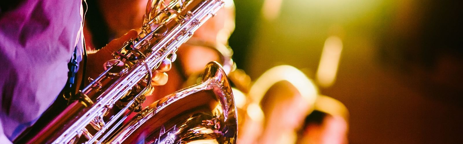 many musicians on the stage playing trumpets with a stage light in the background
