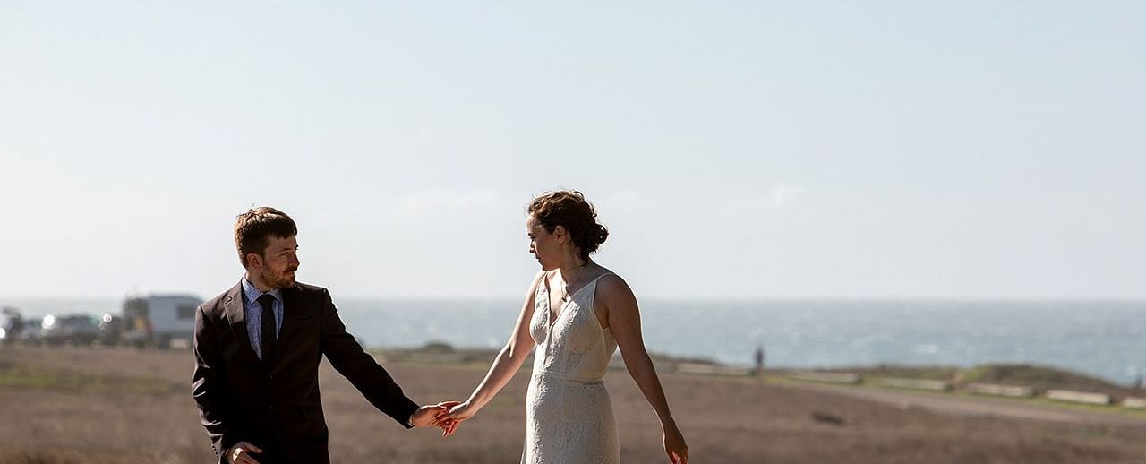 Couple holding hands while walking down a road glowing in the evening light