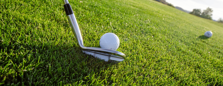 A close-up shot of a golf club and ball on the lush green fairway, ready for a perfect swing.
