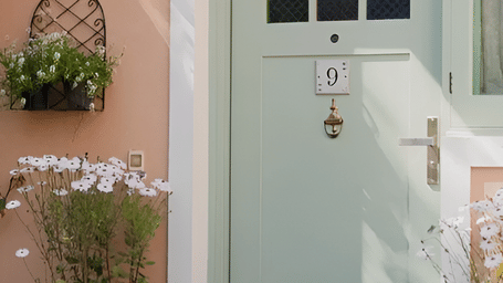 A doorway with a small window above it surrounded by flowering plants at Karma Chalets.