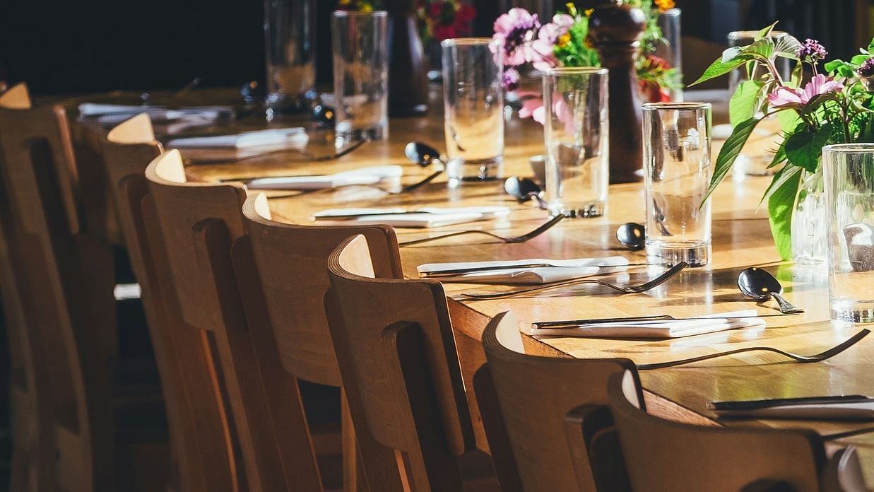 an image of cutlery placed on a  long wooden table 