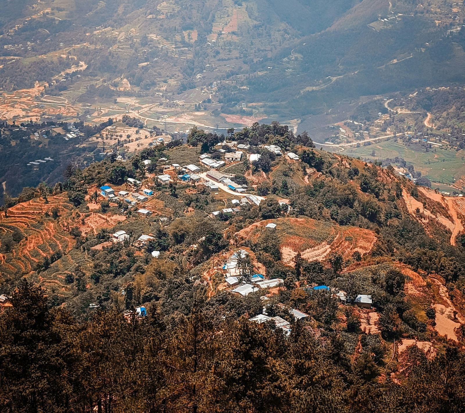 A far out view of Kathmandu Valley perched atop a hill with mountains in the background.