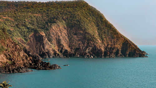 Hill-top view of Cabo de Rama Beach featuring blue ocean water  under clear blue sky