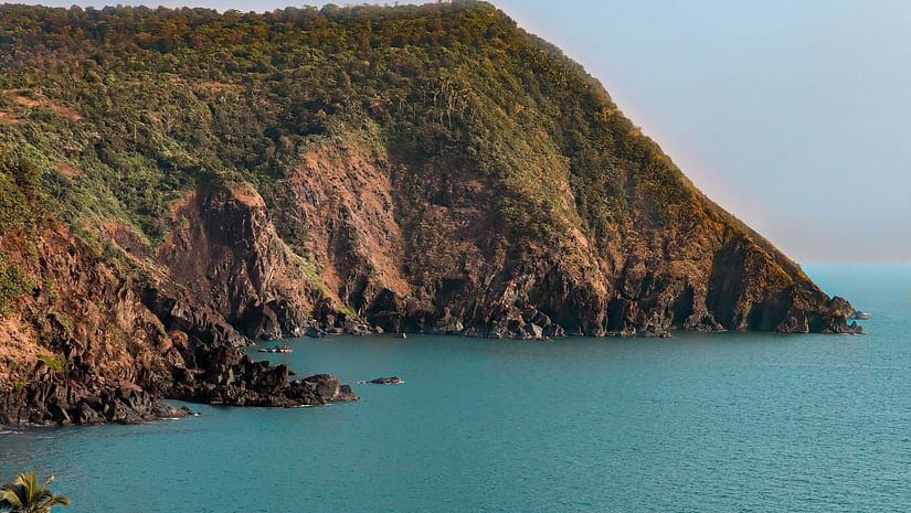 Hill-top view of Cabo de Rama Beach featuring blue ocean water  under clear blue sky