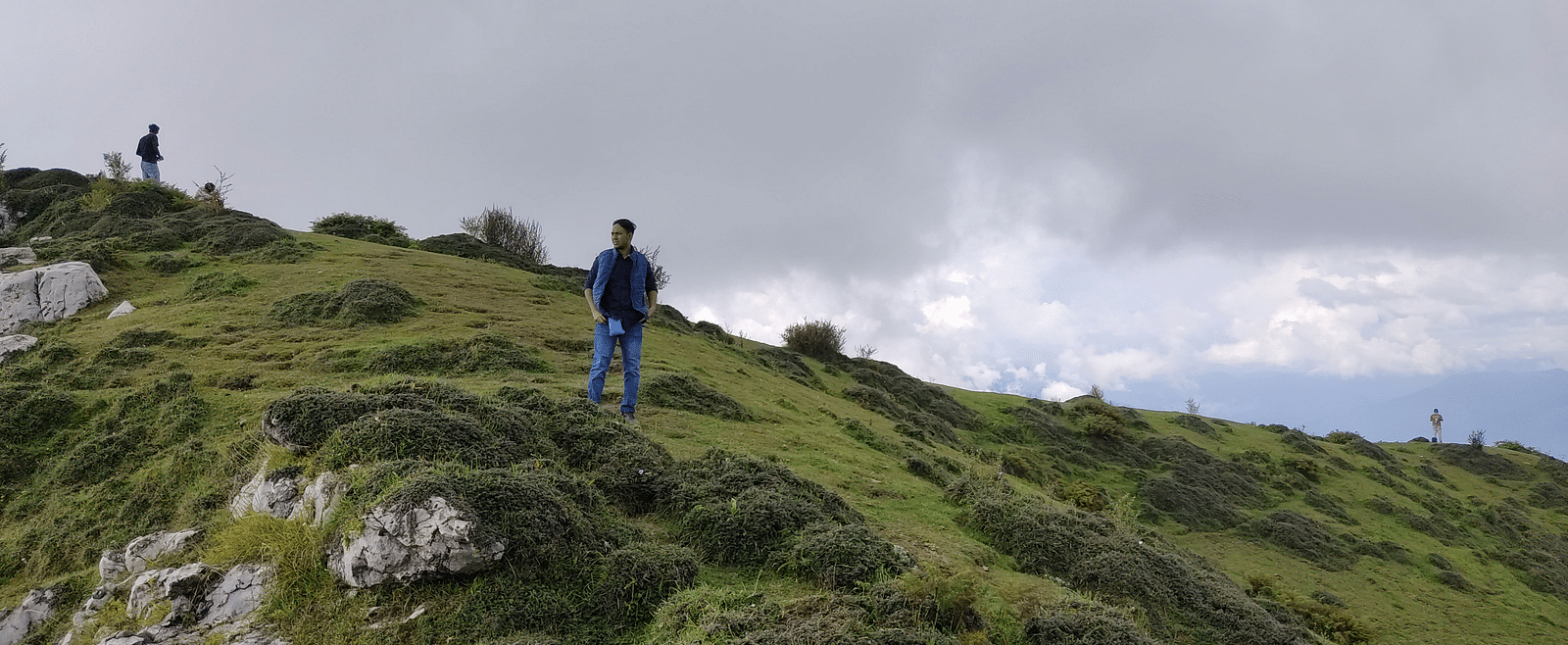 A person standing on a grass-covered mountain.