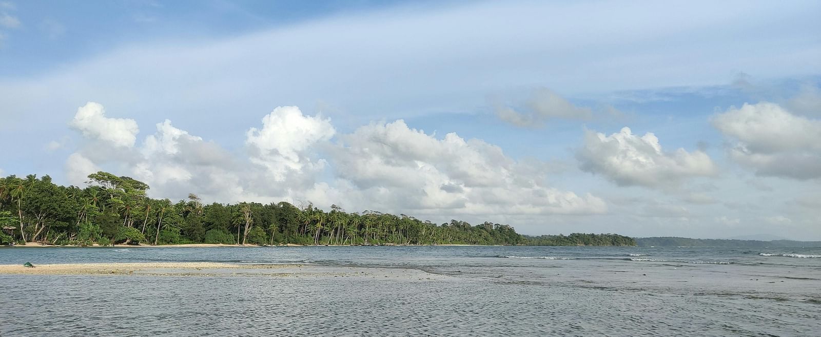 A peaceful stretch of shallow water gently meeting the sandy beach under a clear sky.