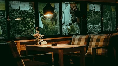 A moody sitting arrangement at a cafe in Manali with two sofas and a wooden table in between them with a hanging light above the tabel.