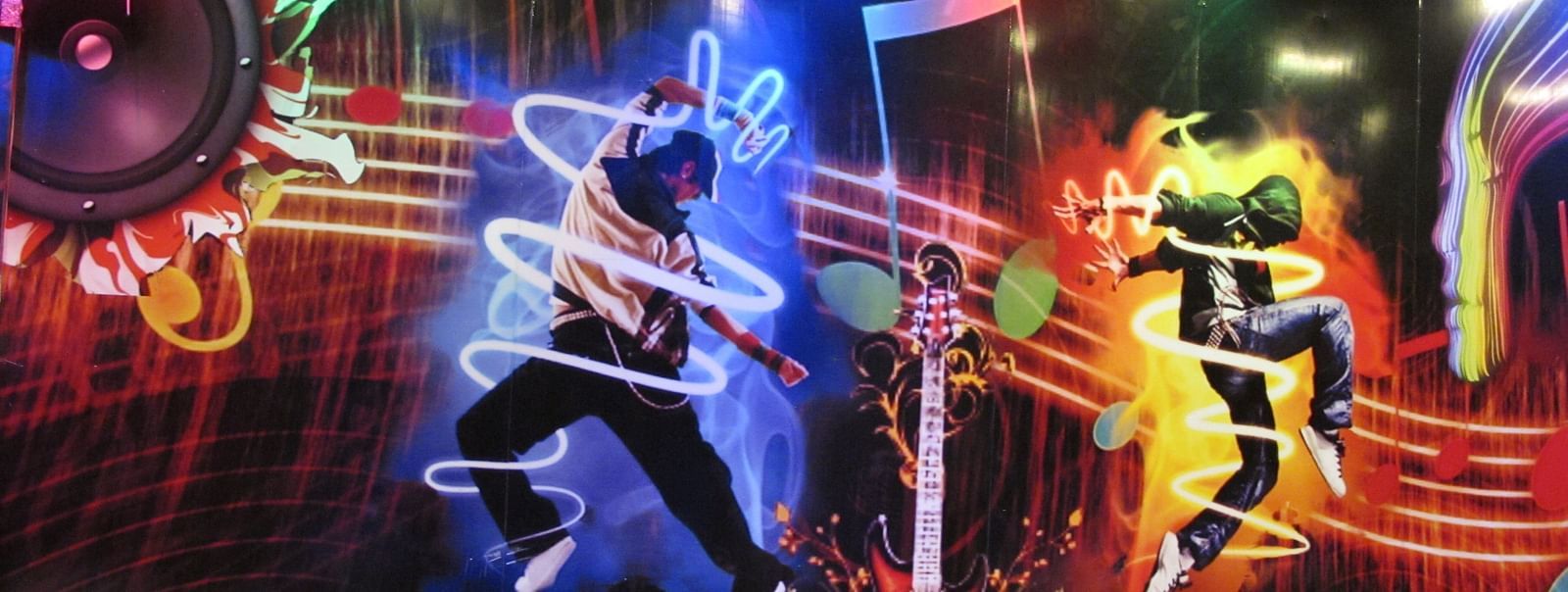A close-up view of the wall mural, showcasing energetic dancers and dynamic light effects - TGI Apple Inn, Jaipur 