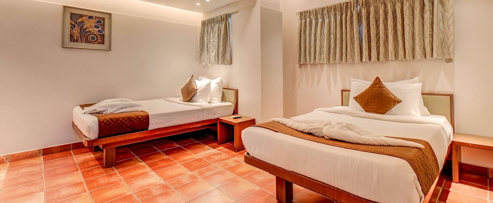 A spacious room at Harigovinda's JNStay with two neatly made beds and window covered by curtains