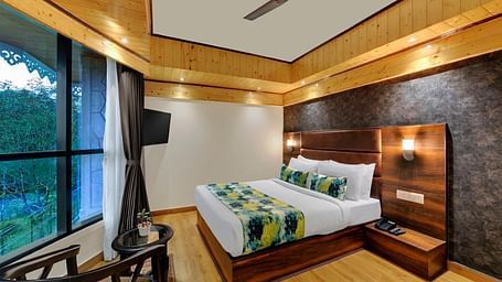An image of Sumitel Queensyard premium room with king size bed, ceiling fan and an expansive window