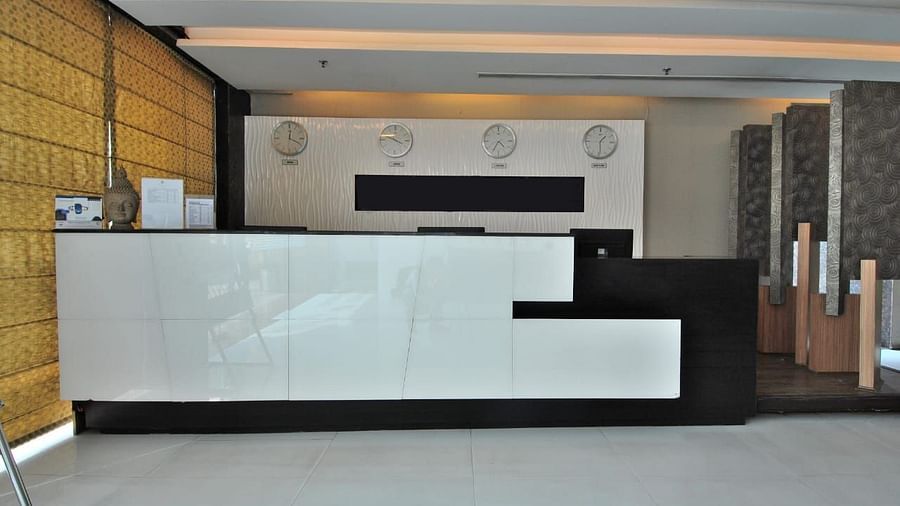 A reception area with a white counter, black accents, and a panelled wall, creating a modern look - VITS Gurugram