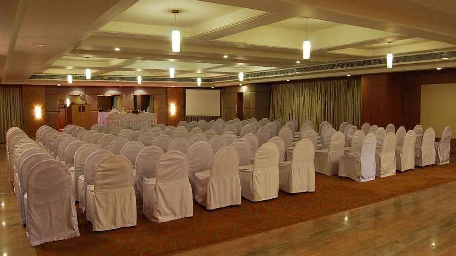 A well-lit banquet hall with neatly arranged chairs and elegant ceiling lights creating a warm ambience - Lords Plaza Ankleshwar