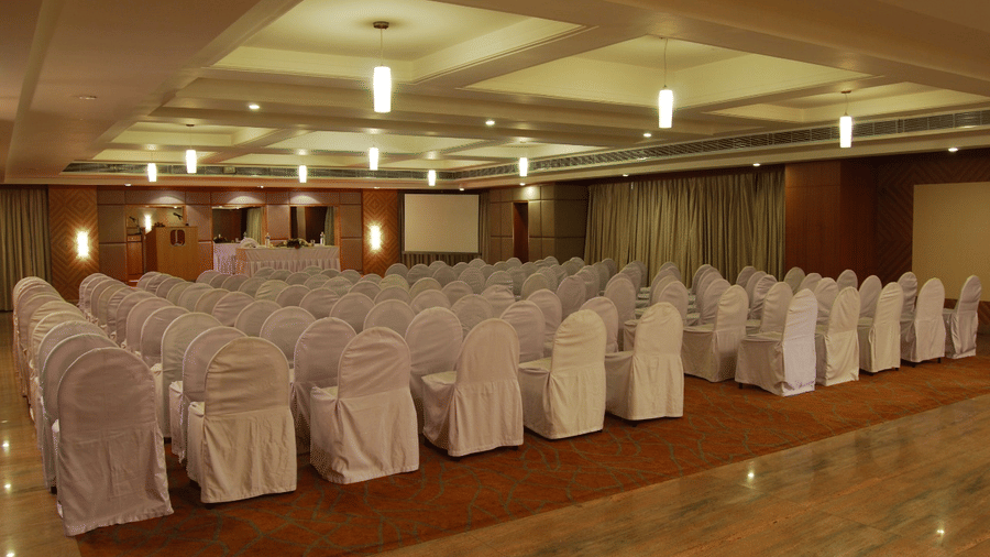 A well-lit banquet hall of Lords Plaza Ankleshwar with theatre style seating and elegant interiors creating a warm ambience
