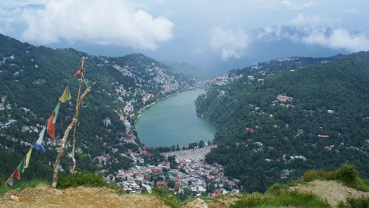 A panoramic view of a mountain landscape with clouds and colorful flags, showcasing a beautiful valley.