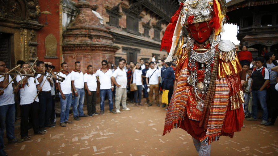 A traditional Newari Lakhey dancer in an ornate costume performing for a crowd in the historic streets of Bhaktapur, Nepal.