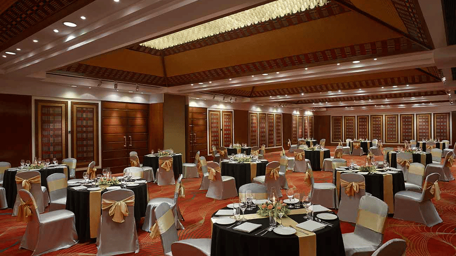 Ballroom at Caravela Beach Resort set up for a wedding reception with round banquet tables, elegant décor, and spacious indoor seating.