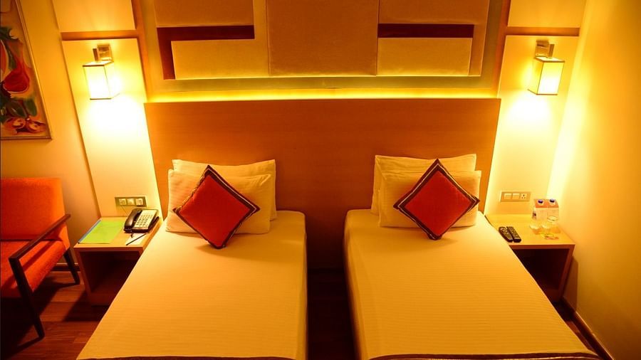 Warmly lit hotel room with two single beds, decorative cushions, modern headboard, bedside tables, and ambient lighting - Citrus Classic, Outer Ring Road, Bangalore
