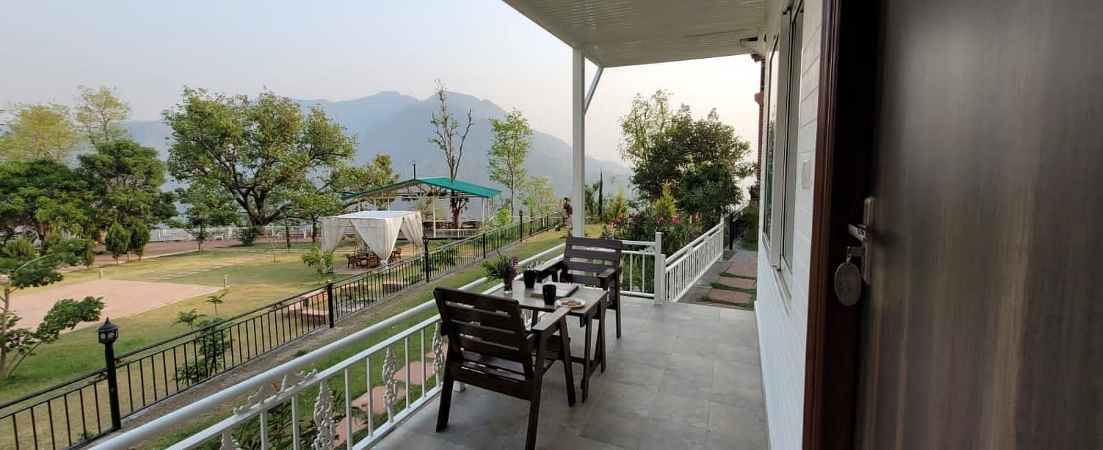 a view of the balcony with chairs and a table on it inside one of the rooms - Neer Ganga Resorts