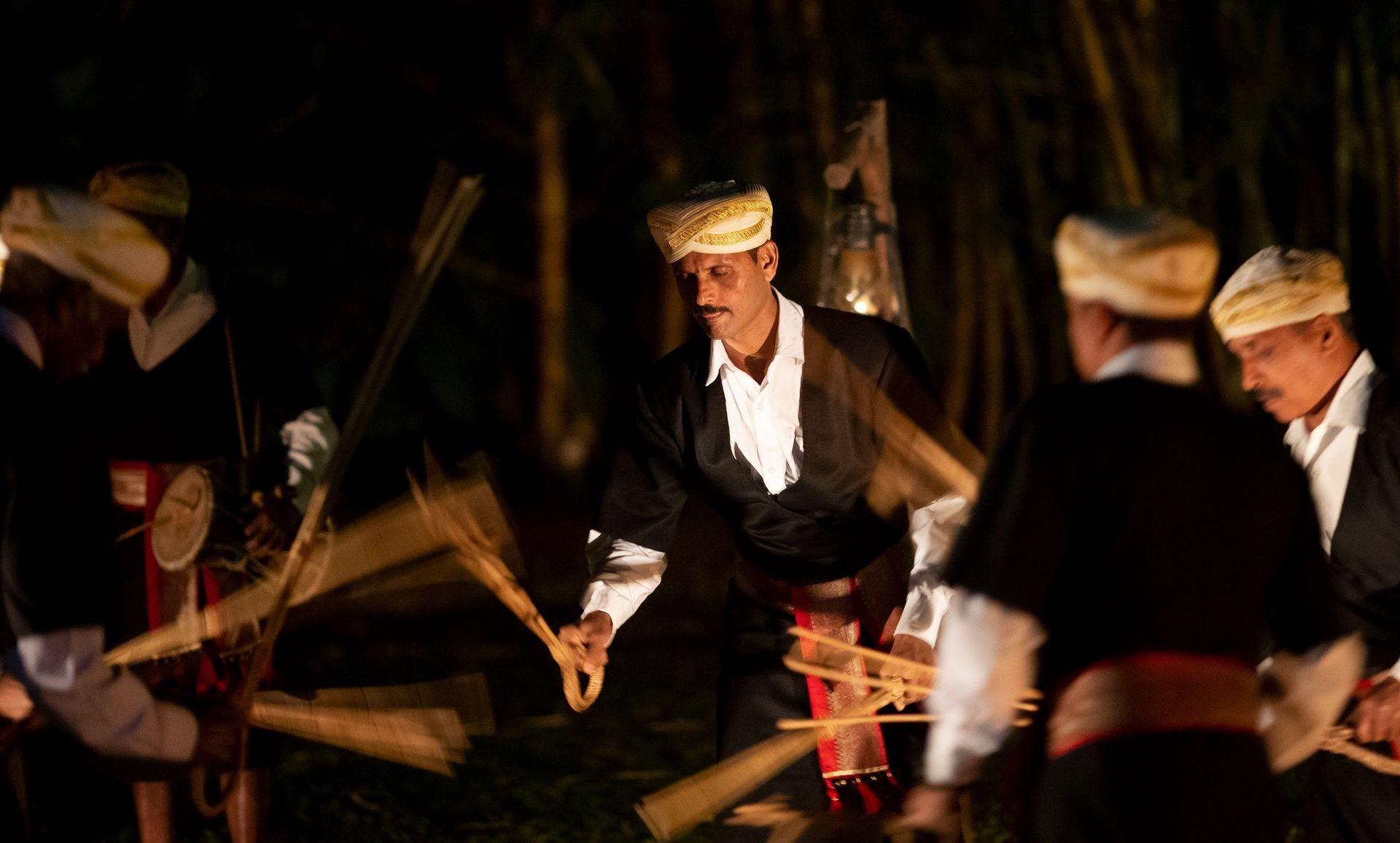 Kodava folk dancers performing with sticks at night.