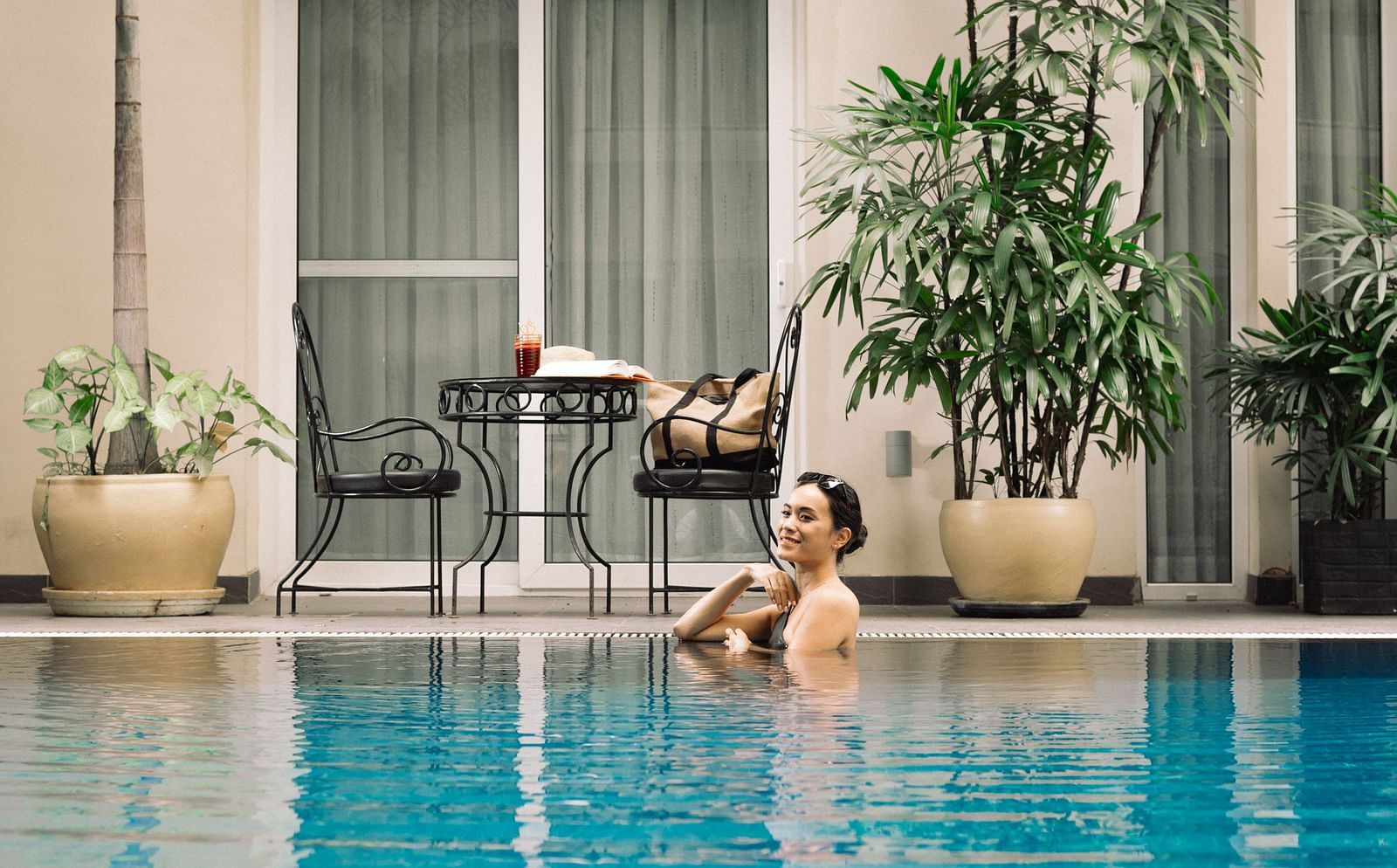 A woman resting in a swimming pool with chairs in the background | Central Mansions, Phnom Penh