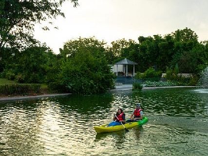 Two people paddling a yellow kayak in a calm lake surrounded by trees.