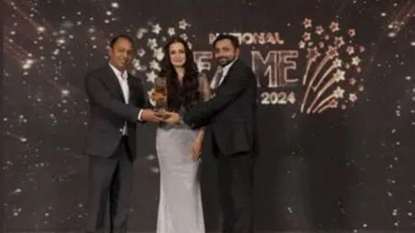 A group of people posing on stage during an award event under a “Brands Impact” banner at Illara Hotels & Spa.