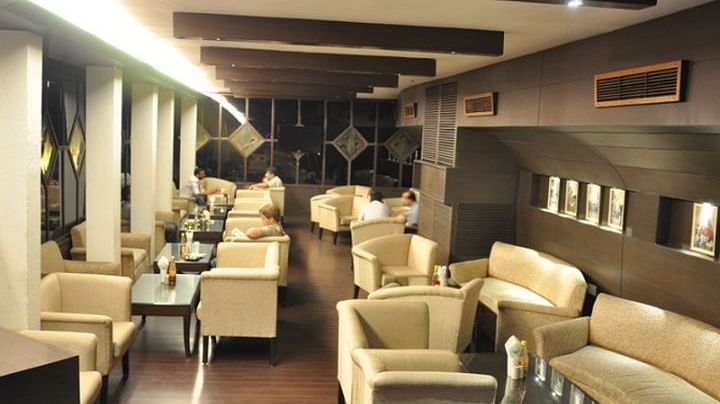 A brightly lit seating area with white leather sofas and central air-conditioning at 24 Karats Bar - Hotel Gold, Panipat