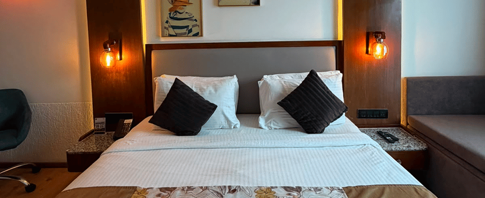 Deluxe Room with a king bed dressed in a floral runner beneath cove lighting and framed portrait art