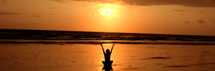 a woman doing beachside yoga near the overlapping waves and the sun setting in the background - Azaya Beach Resort Goa
