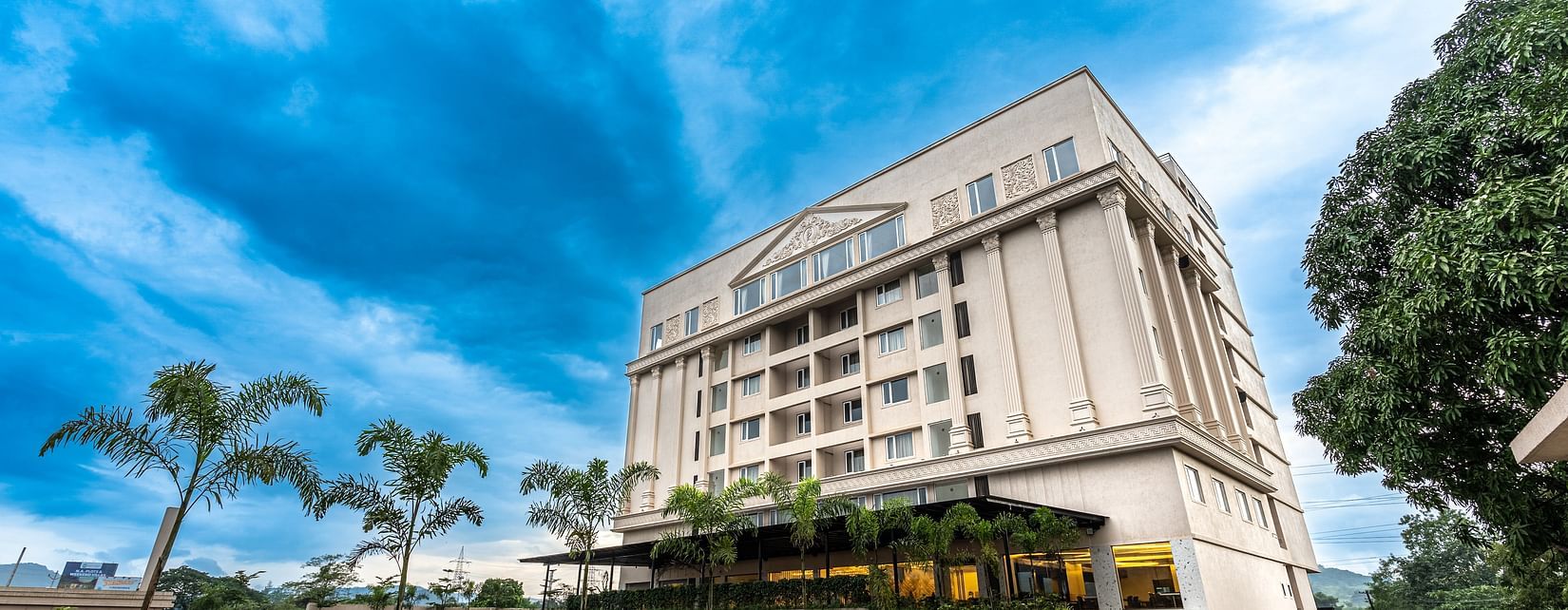 facade of a hotel building with blue sky as the  backdrop - Mastiff Grand - The Sia Palace Suites & Banquets, Khopoli