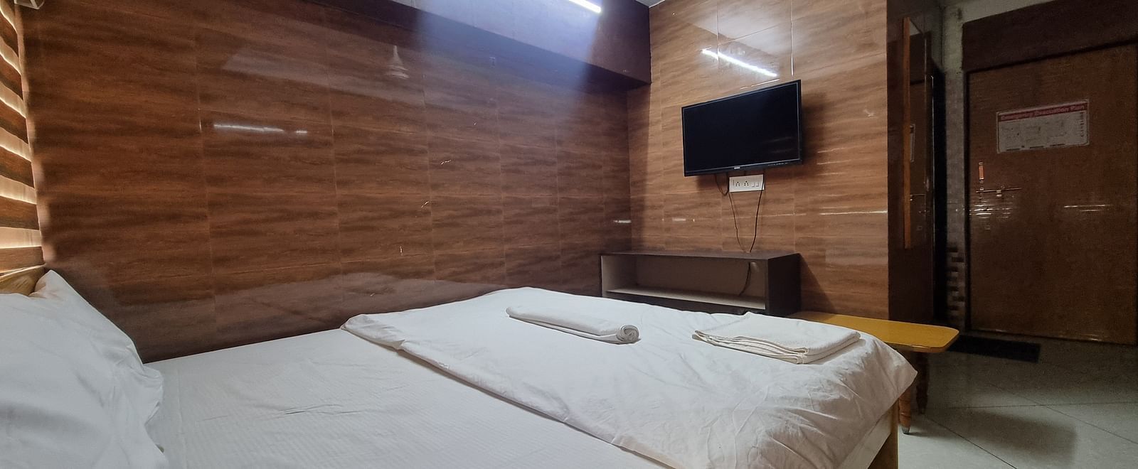 Full view of the bedroom at the Dream Vision Guest House facing towards a wall mounted television.