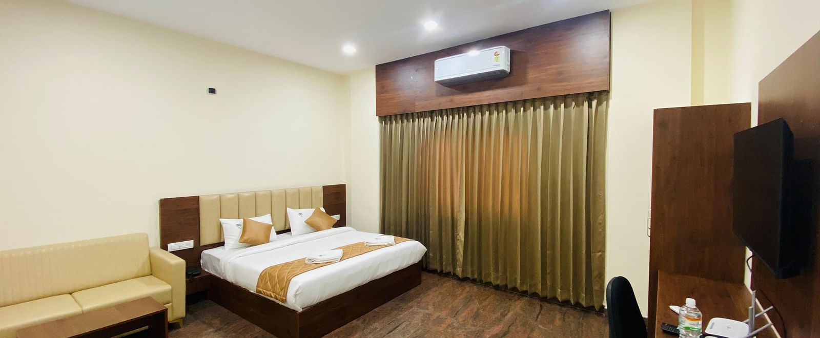 A double bed in a room area with stylish lighting, AC, rustic floor, seating and curtains at Hotel Sahara Tree.