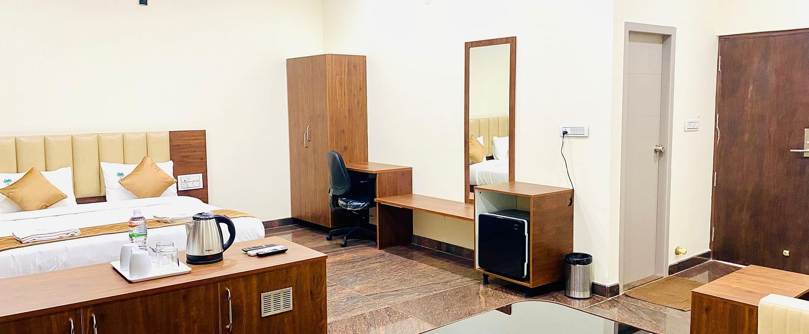 This spacious room at Hotel Sahara Tree includes a bed, wardrobe, and dressing table.