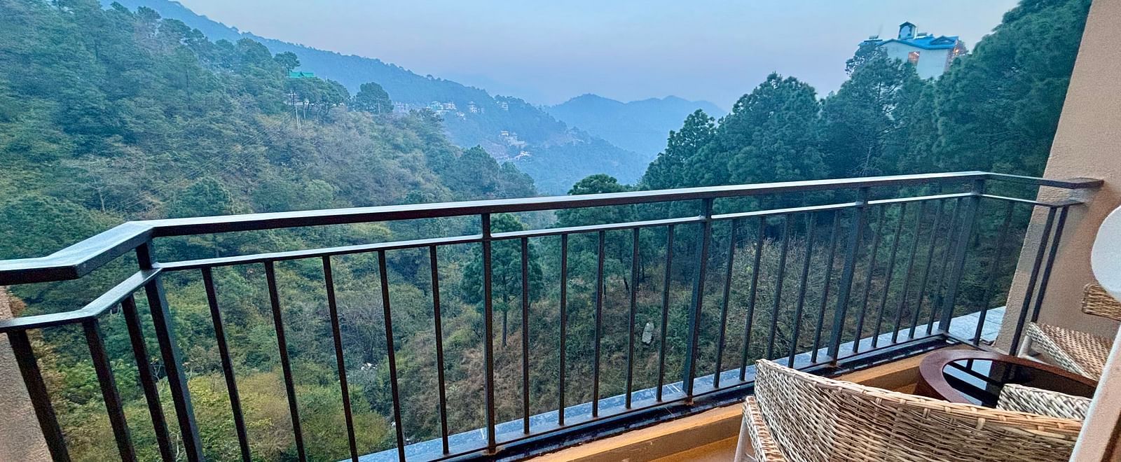 Balcony view with a chair overlooking lush green hills and a serene valley at ARNISA Boutique Hotel