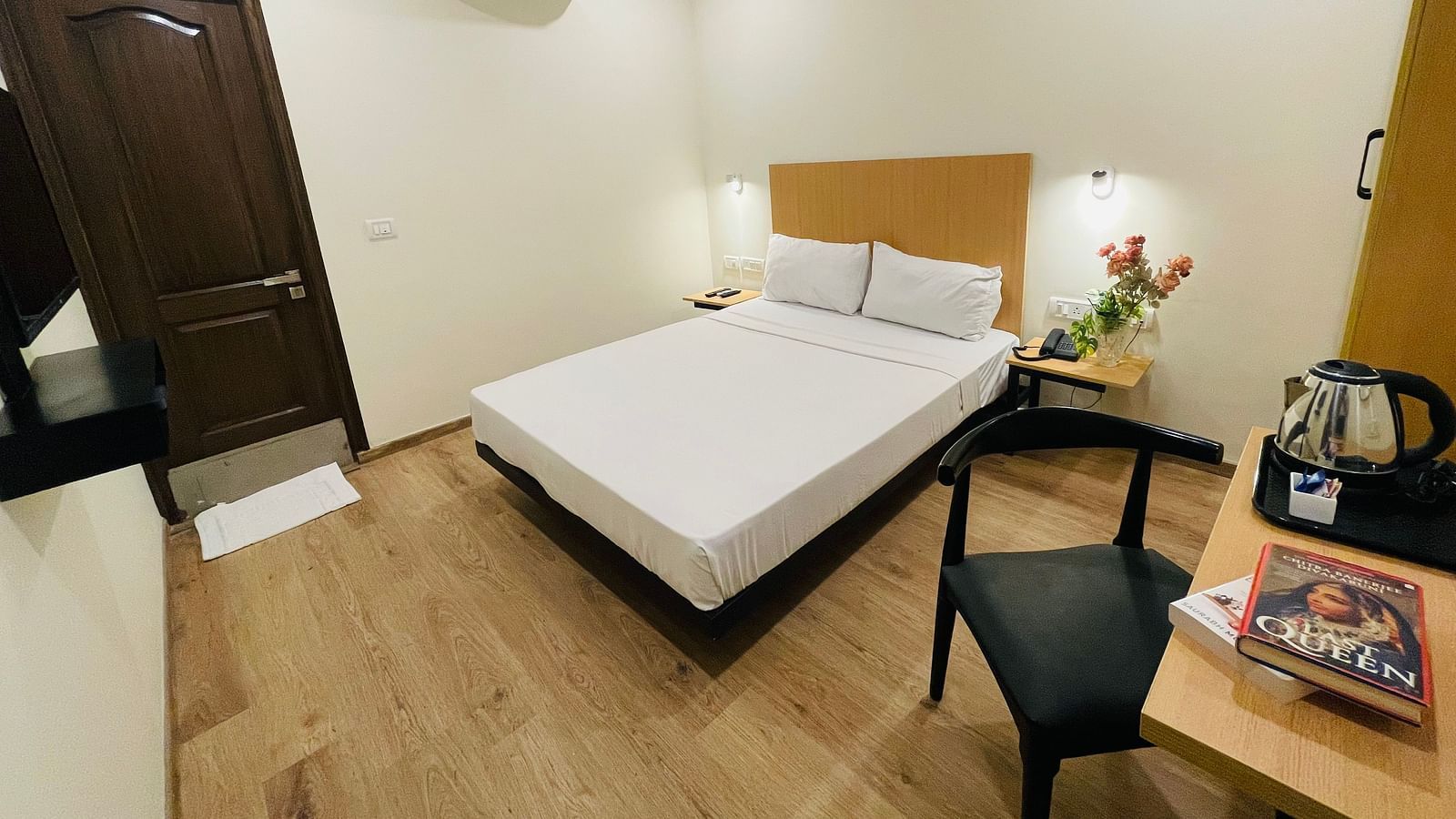 A double bed and a work desk on which a tea and coffee maker is placed at Sanctum Suites Richmond Road, Bangalore