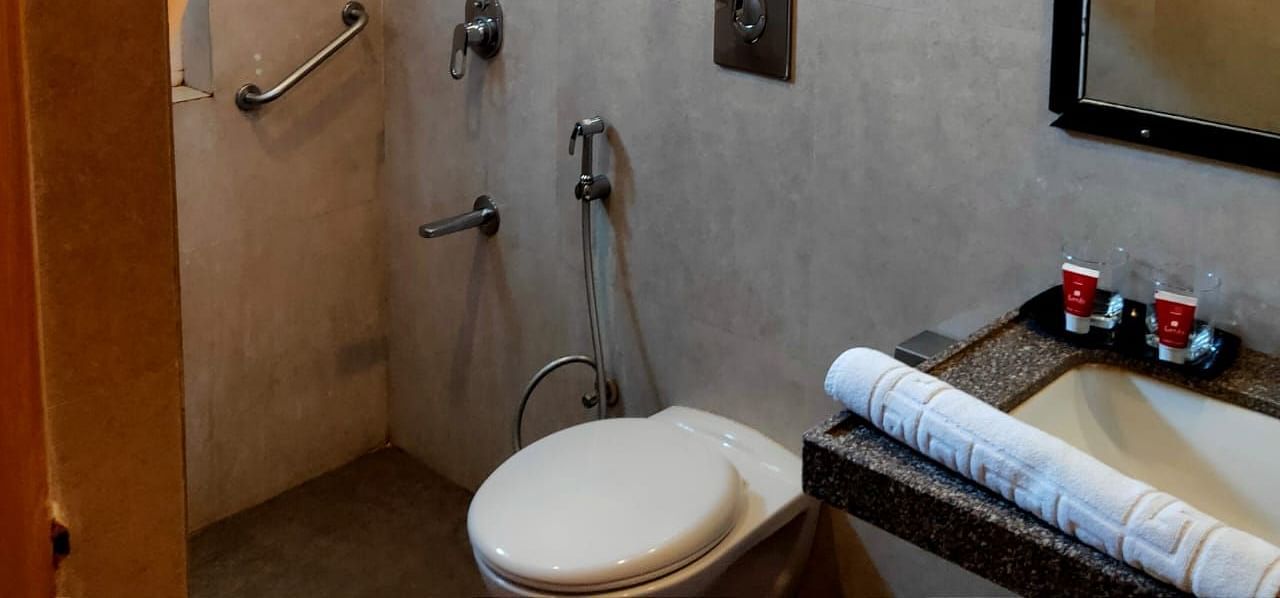 A clean and modern bathroom at Rang Lords Inn, equipped with a shower, toilet, and sink, showing the hotel's attention to guest convenience