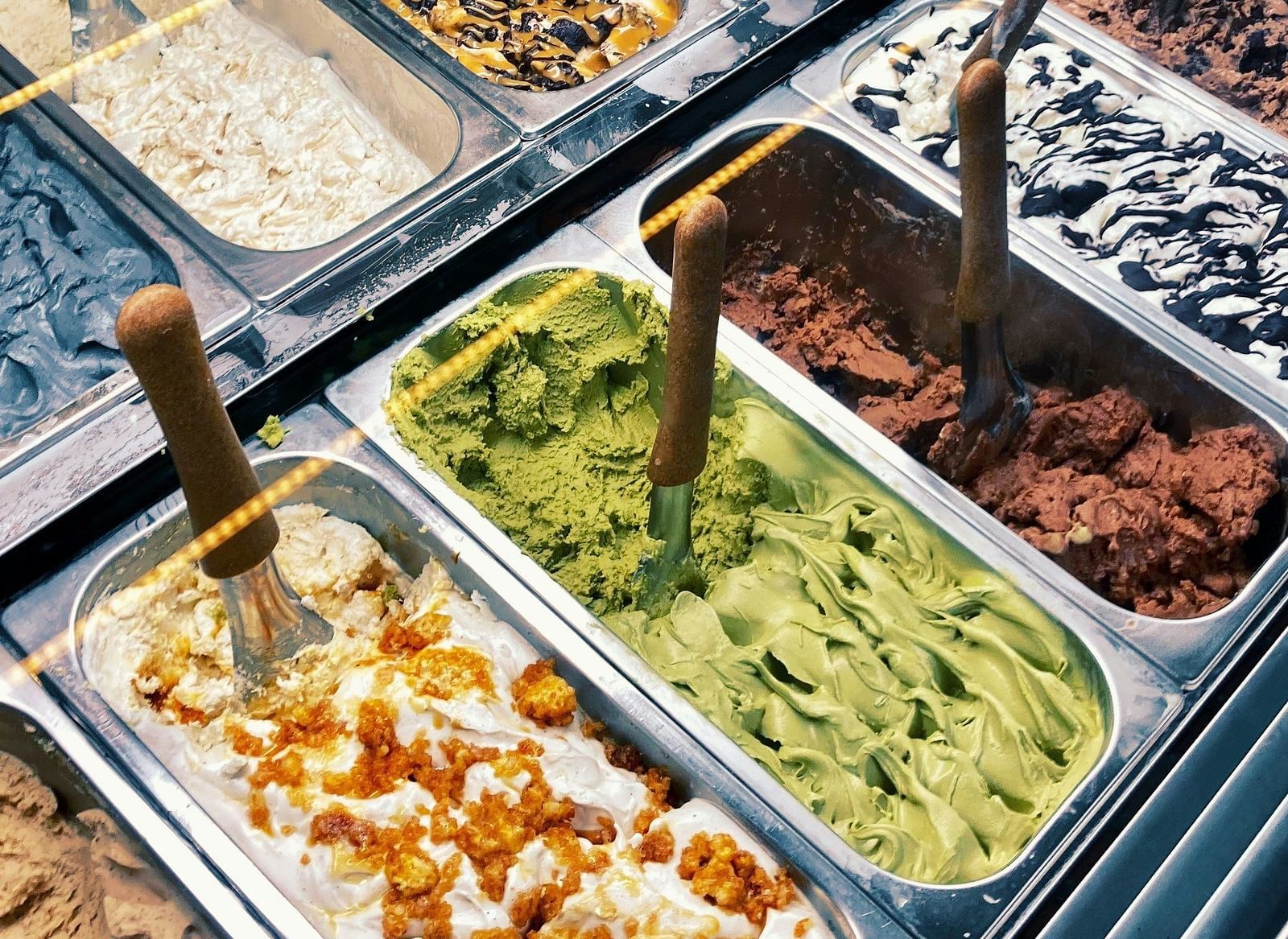 A colourful assortment of ice creams in metal trays, showcasing a variety of flavours.