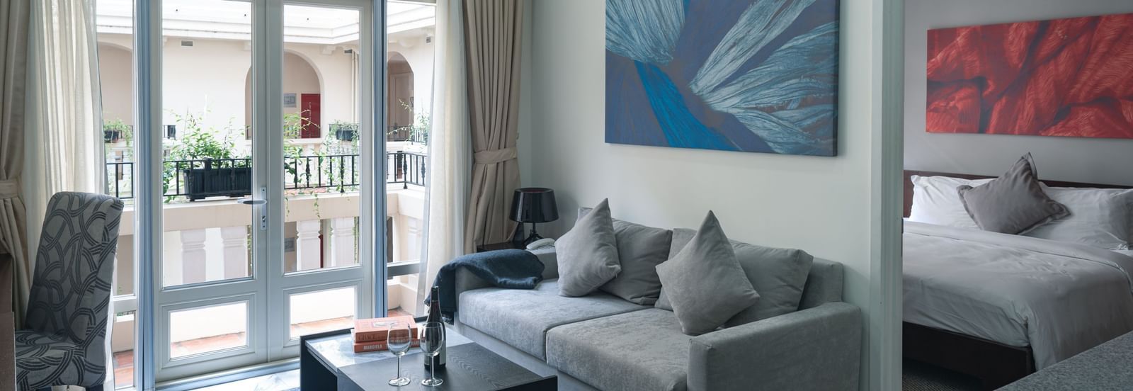 A living room area with a grey sofa, a coffee table, and a painting on the wall | Two-bedroom Suite | Central Mansions, Phnom Penh