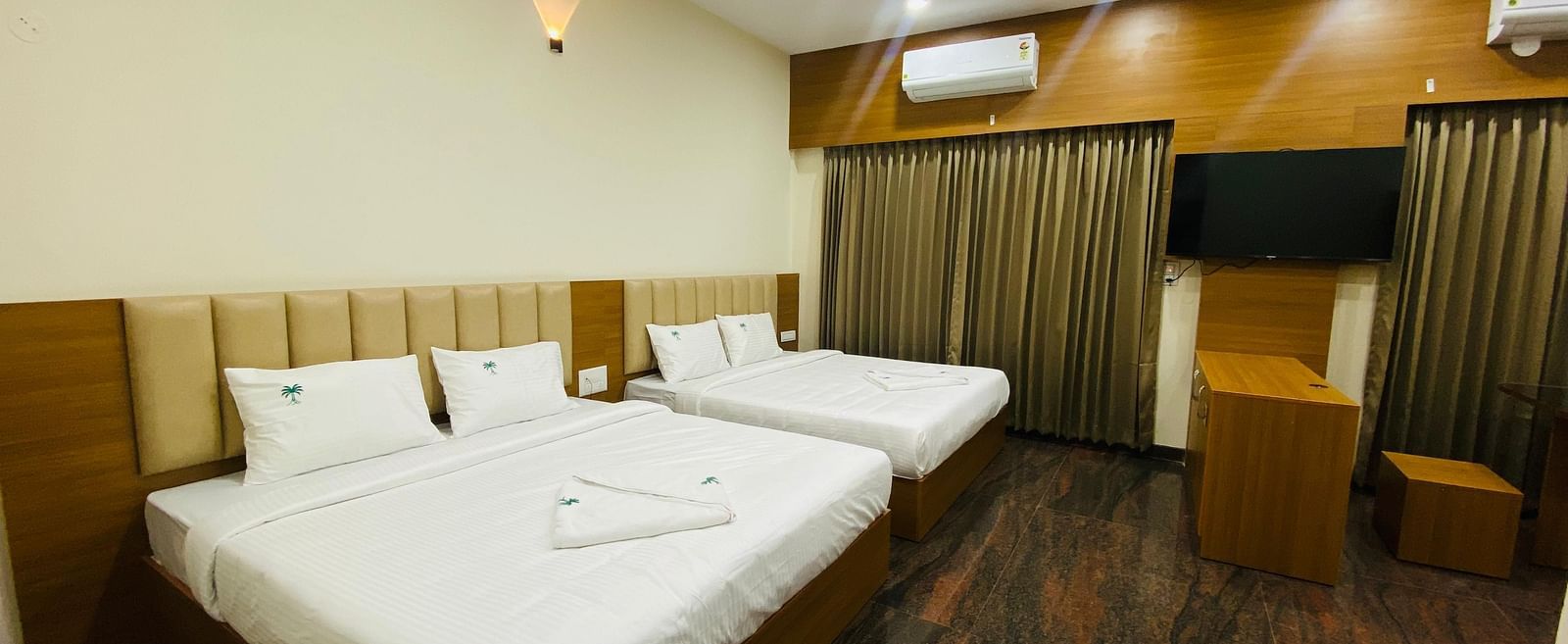 Elegant king-size bedroom with rich wooden flooring and soft lighting at Hotel Sahara Tree.