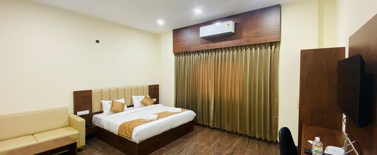 A double bed in a room area with stylish lighting, AC, rustic floor, seating and curtains at Hotel Sahara Tree.