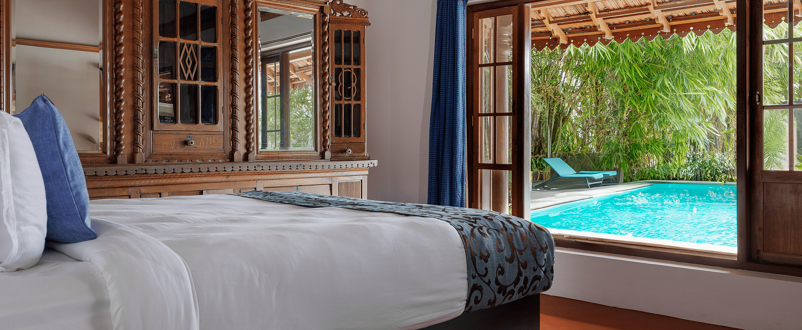 A shot of a room taken from an angle showcasing the bed facing a huge window with the view of the pool outside - BluSalzz Villas - Muhamma Resort, Alleppey