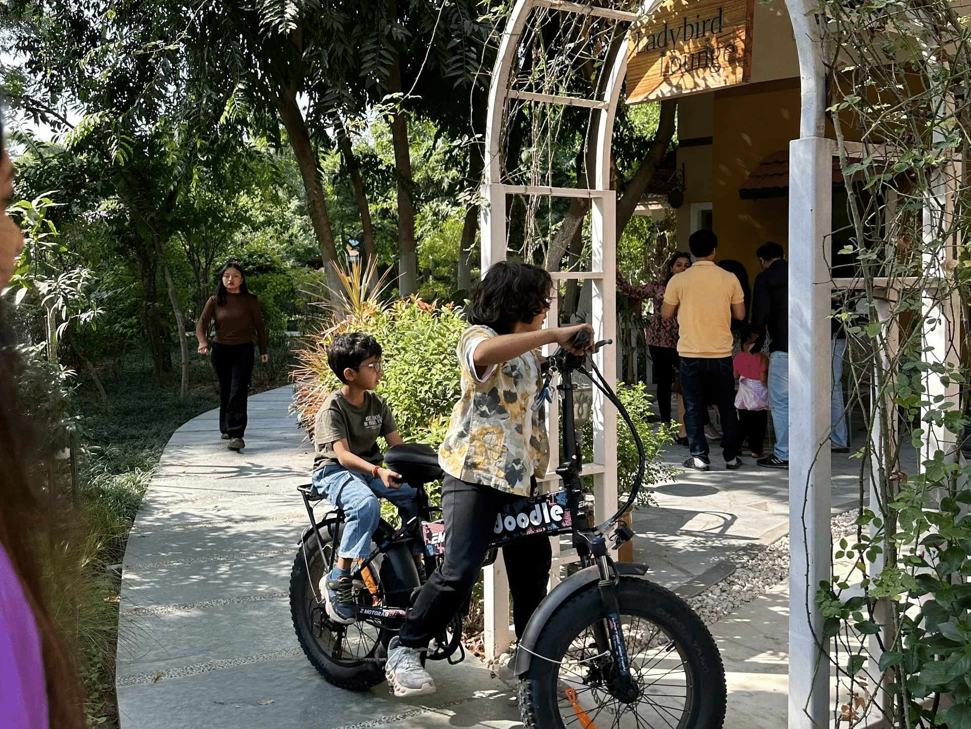 Children riding bicycles near an arched entryway at Karma Chalets.