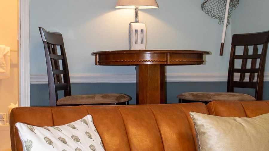living area with tan leather sofa, nautical decor, fishing nets and vintage boat propeller at Hartstone Inn.