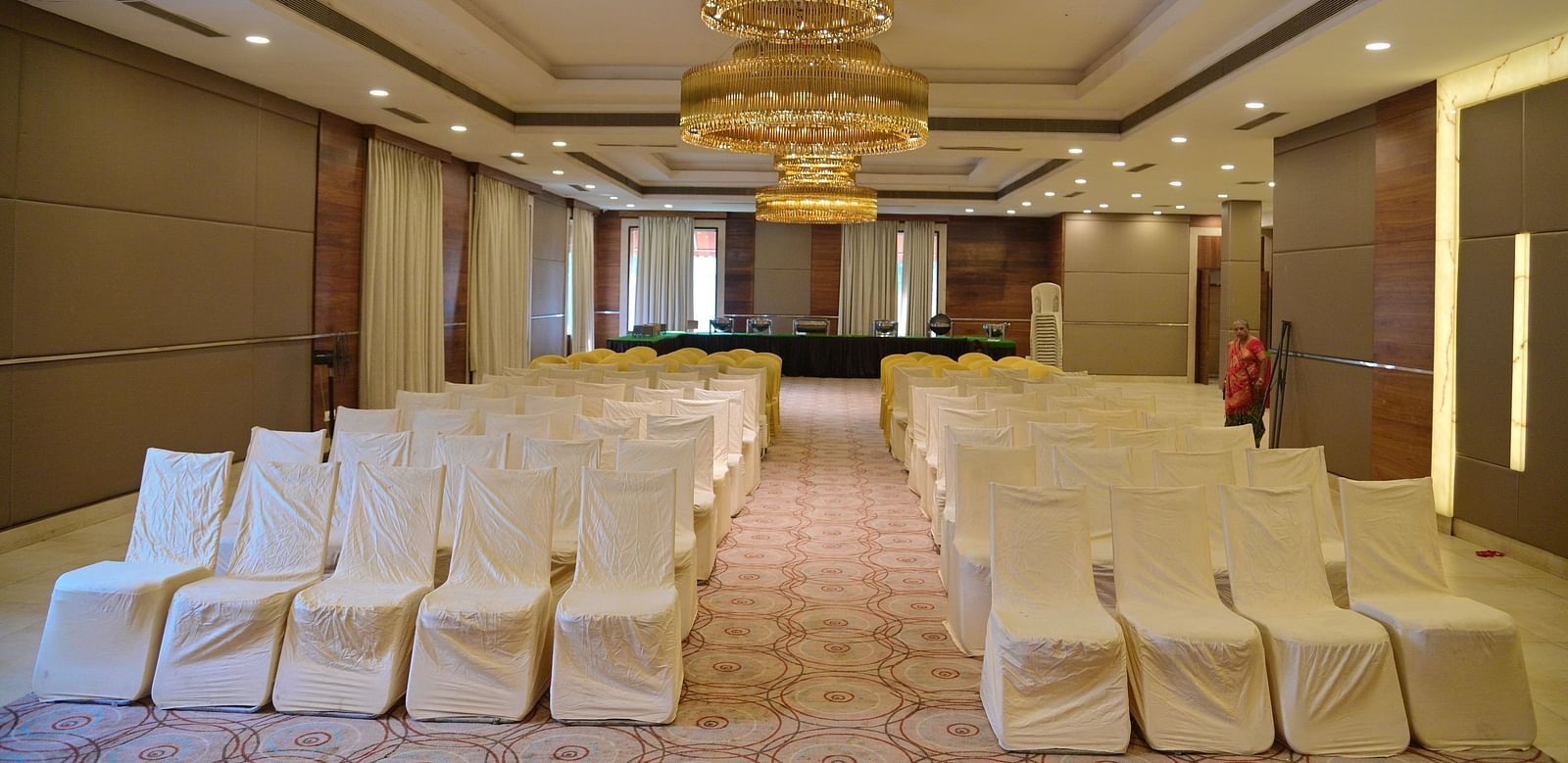Banquet hall with rows of white chairs and a chandelier, prepared for an event at Rang Lords Inn Bharuch