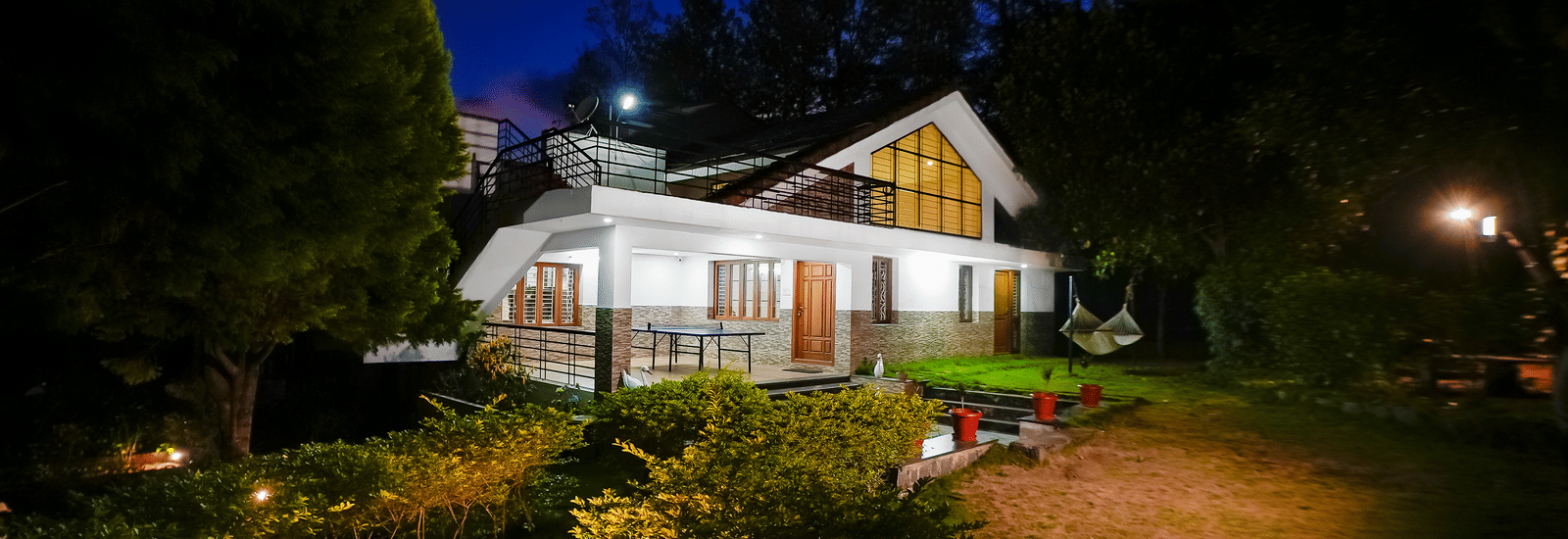 Facade view of WOW Bungalow, Yercaud, at night with a garden area.