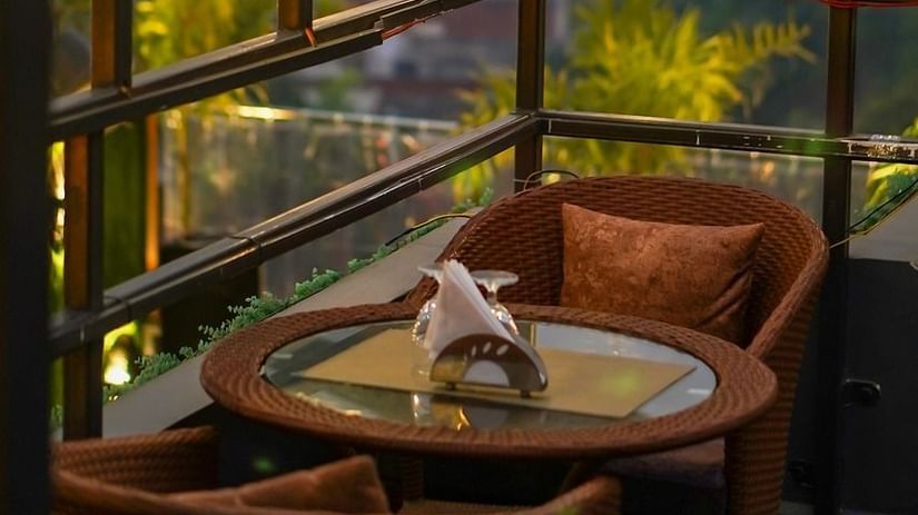 Two chairs facing each other on a terrace with warm lights besides it on a late evening.