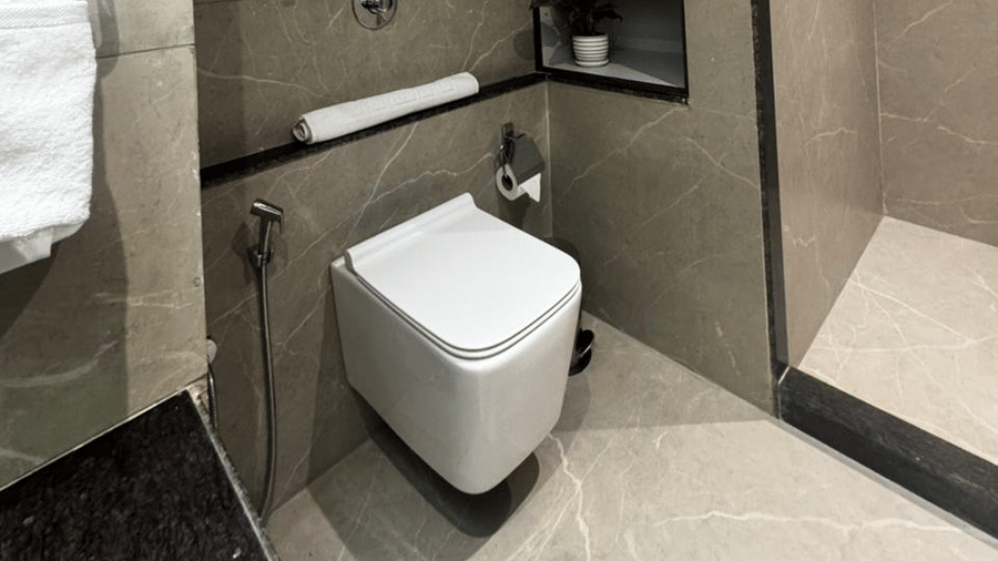 Wide view of a modern bathroom with marble-tiled walls and vanity - Lords Swastik Studio, Kodinar